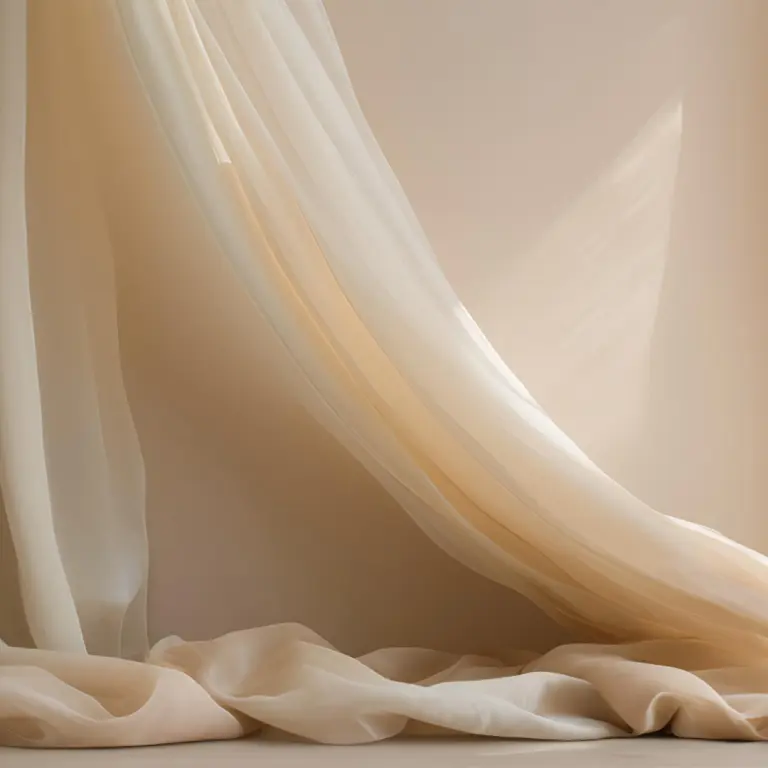 Dettaglio sartoriale di un tessuto per tende leggero e velato di colore beige, che cade in morbide pieghe sul pavimento con luce naturale calda.